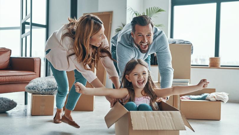 Stock photo of a cheerful young family smiling and unboxing their stuff while moving into a new home.