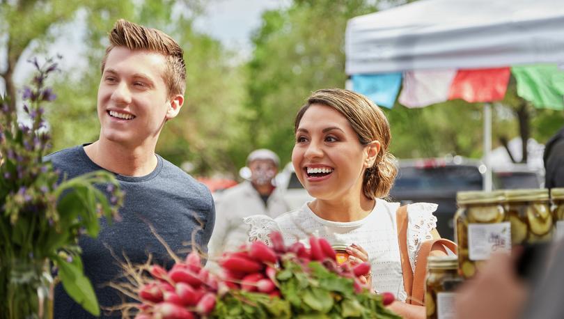 Young couple smiling while at a local farmer's market. 