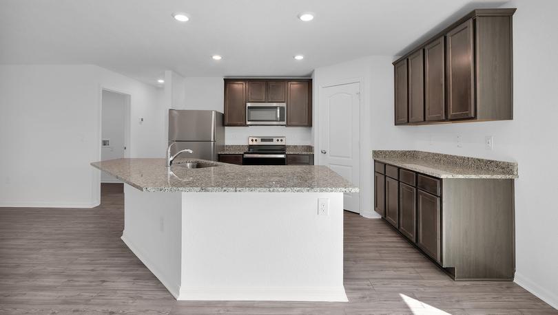 Kitchen photo showcasing large island, granite countertops and spacious brown cabinets. 