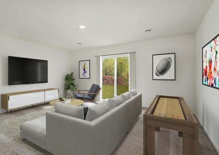 Photo of a walkout basement game room with a sectional sofa, carpet, media cabinet and wall-mounted TV and shuffleboard table, with a sliding glass door.