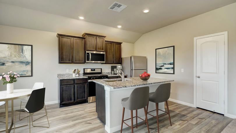 Staged kitchen with brown cabinetry and stainless steel appliances.