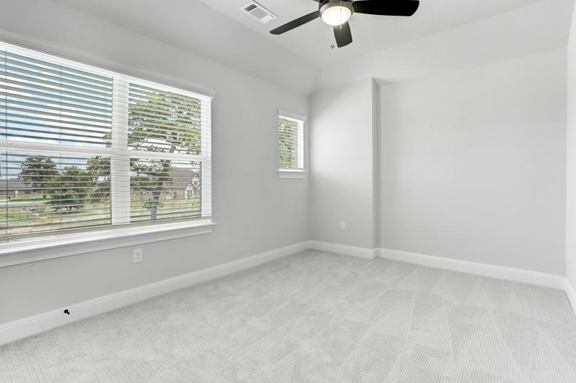 Guest bedroom with large windows, a ceiling fan, and gray carpet.