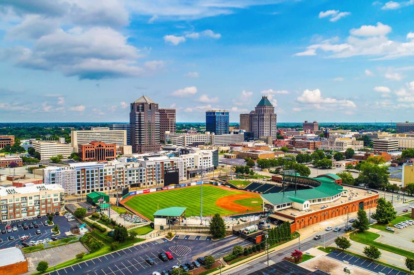 Downtown Greensboro, North Carolina cityscape photo taken from the sky showing skyscrapers, sports grounds, and apartment buildings