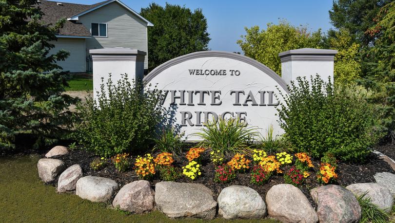Entrance monument to White Tail Ridge in summer with flowers and rock border landscaping.