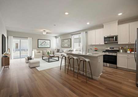 Staged home with an open layout featuring white cabinetry in the kitchen and a bright living room.
