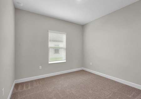 Carpeted secondary bedroom with one window and recessed lighting.