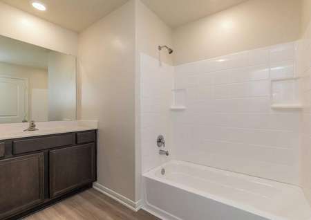 Sabine bathroom with white shower and bathtub unit, brown cabinet, and white vanity top