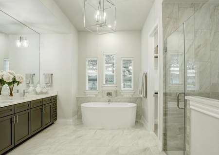 Staged master bath with white freestanding tub, luxury lighting and white tile floors.