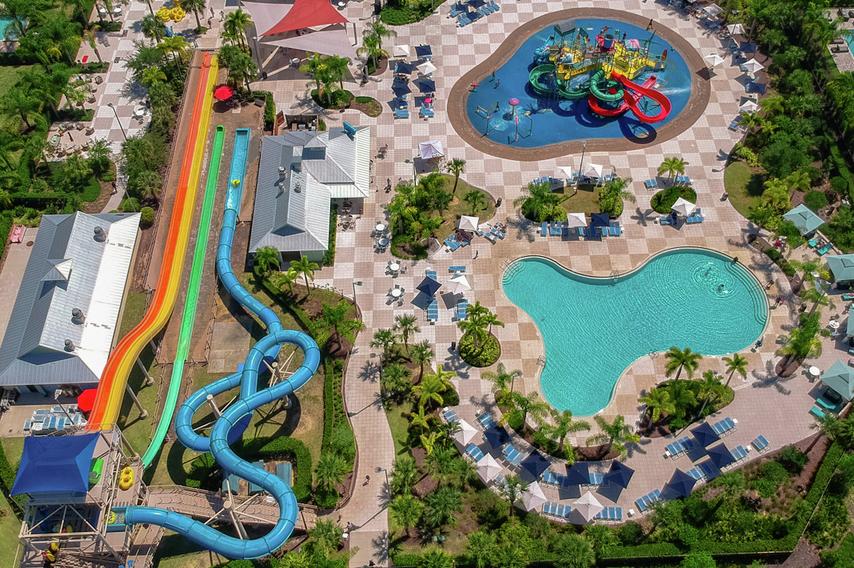 Drone shot overlooking 10-acre water park with water slides, a children's playground with splash pad, a swimming pool and multiple dining options. 