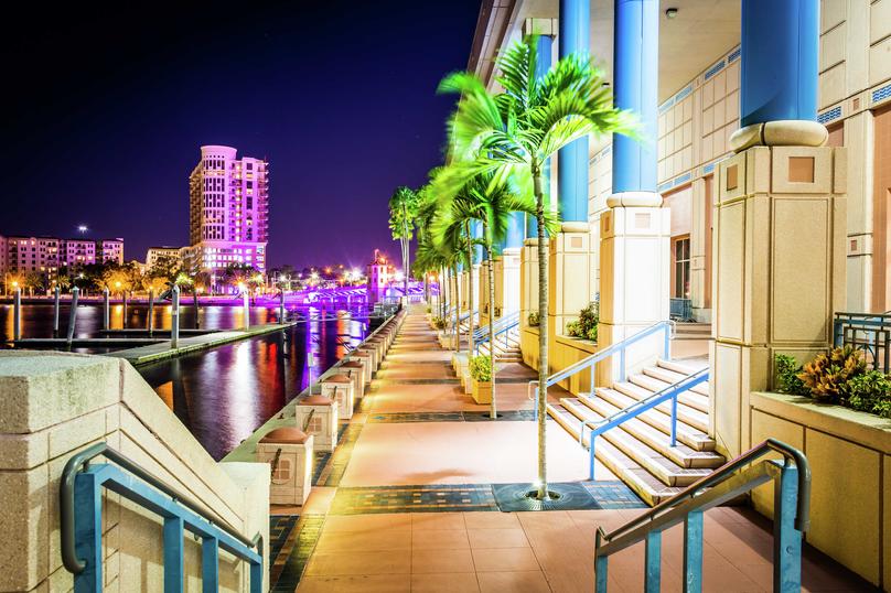 Tampa, Florida Convention Center and Riverwalk at night with purple-lit buildings in background
