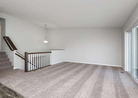 Interior photo of family room with sliding glass door and staircase visible.