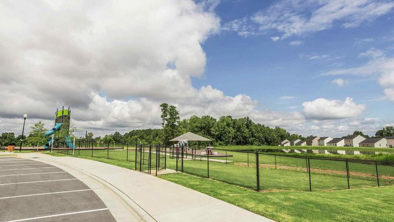 Parking lot infront of a grass field, a dog park and a children's playground in the Autumn Lakes community.