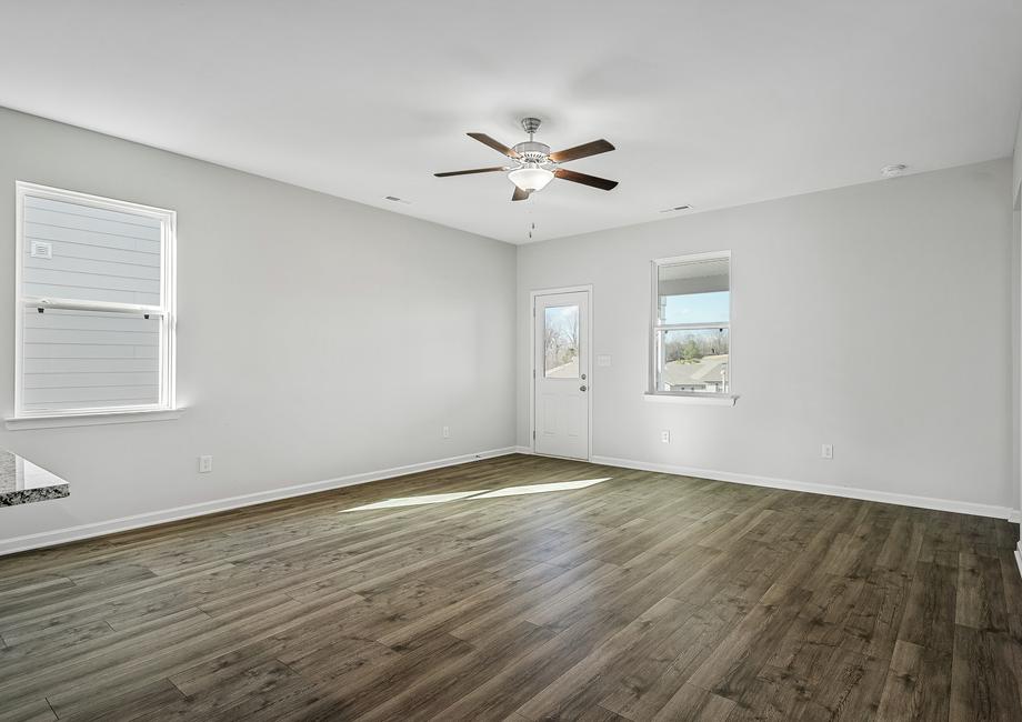 The spacious family room has a ceiling fan and plank flooring.