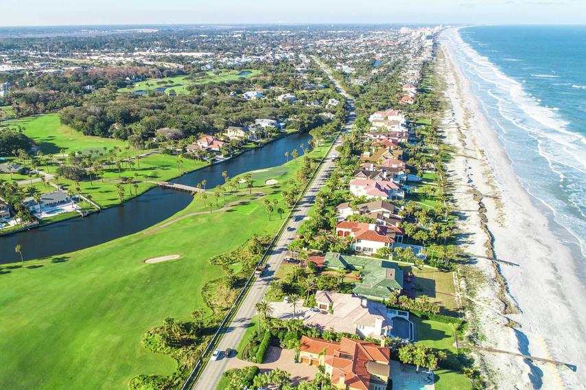 Jacksonville, Florida Ponte Vedra Beach aerial view showing a green grassy golf course, homes lining the beachfront, and residential neighborhoods in the distance