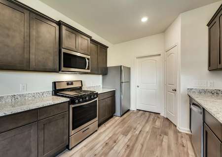 The kitchen has a full suite of stainless steel appliances and modern brown cabinetry.