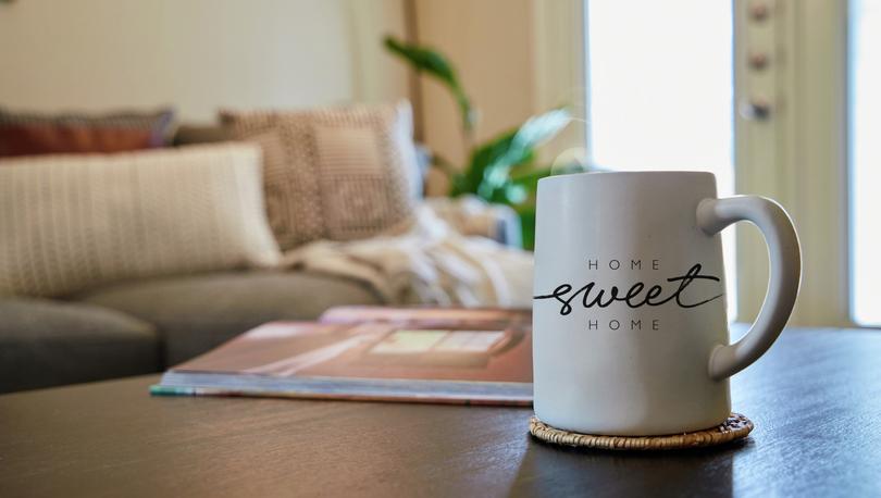 Home sweet home coffee mug on coffee table with couch in the background. 