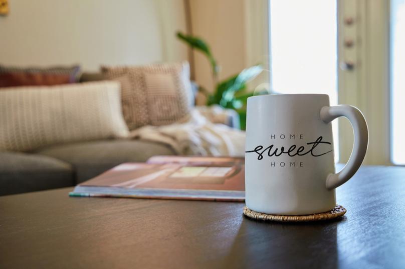 Home sweet home coffee mug on coffee table with couch in the background. 