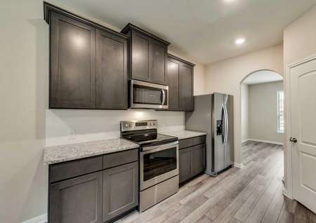 Ozark kitchen finished with stainless steel appliances, brown wood cabinets, and light granite counters