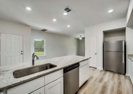 An open-concept kitchen with stainless steel appliances overlooking the home's family room. 
