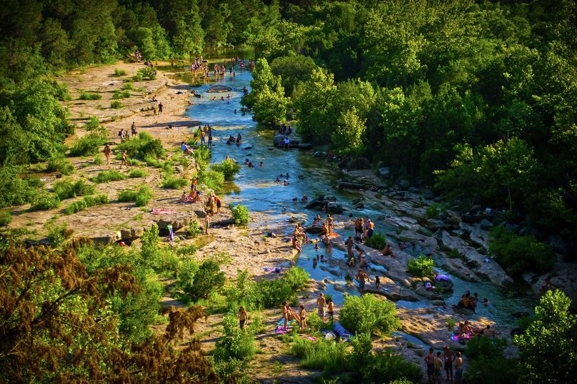 Austin, Texas Barton Creek greenbelt summer fun with numerous people enjoying the water, sunbathing on the shores, and swimming
