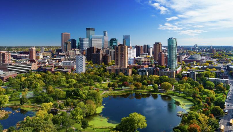 Minneapolis, Minnesota downtown cityscape showing park with ponds, green grass and paths, and plenty of trees