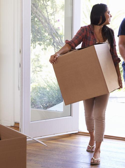 A young couple carries moving boxes into their new home.