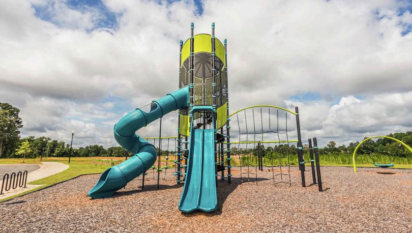 Blue and yellow children's play area in the Autumn Lakes community with wood chips surfacing.