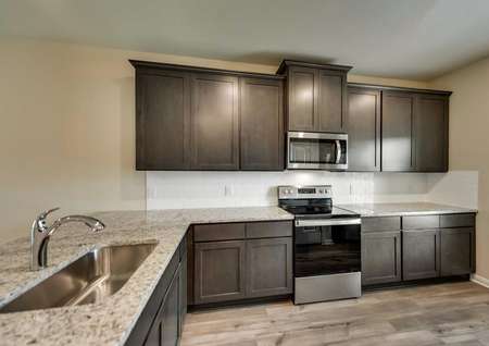 Kitchen with white tile back splash, brown cabinets and stainless steel appliances.